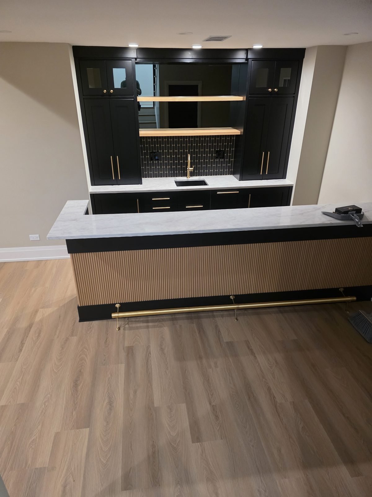 Basement bar with a fluted front panel and floating white oak shelves