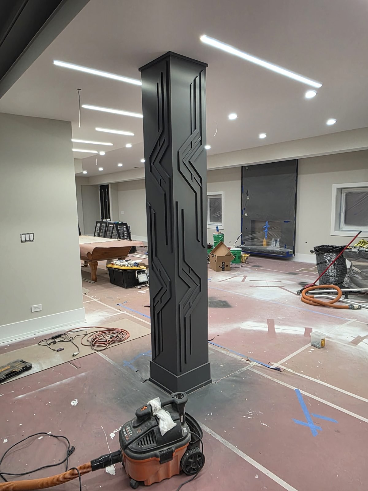 Structural column wrapped in charcoal panels with deco relief detail